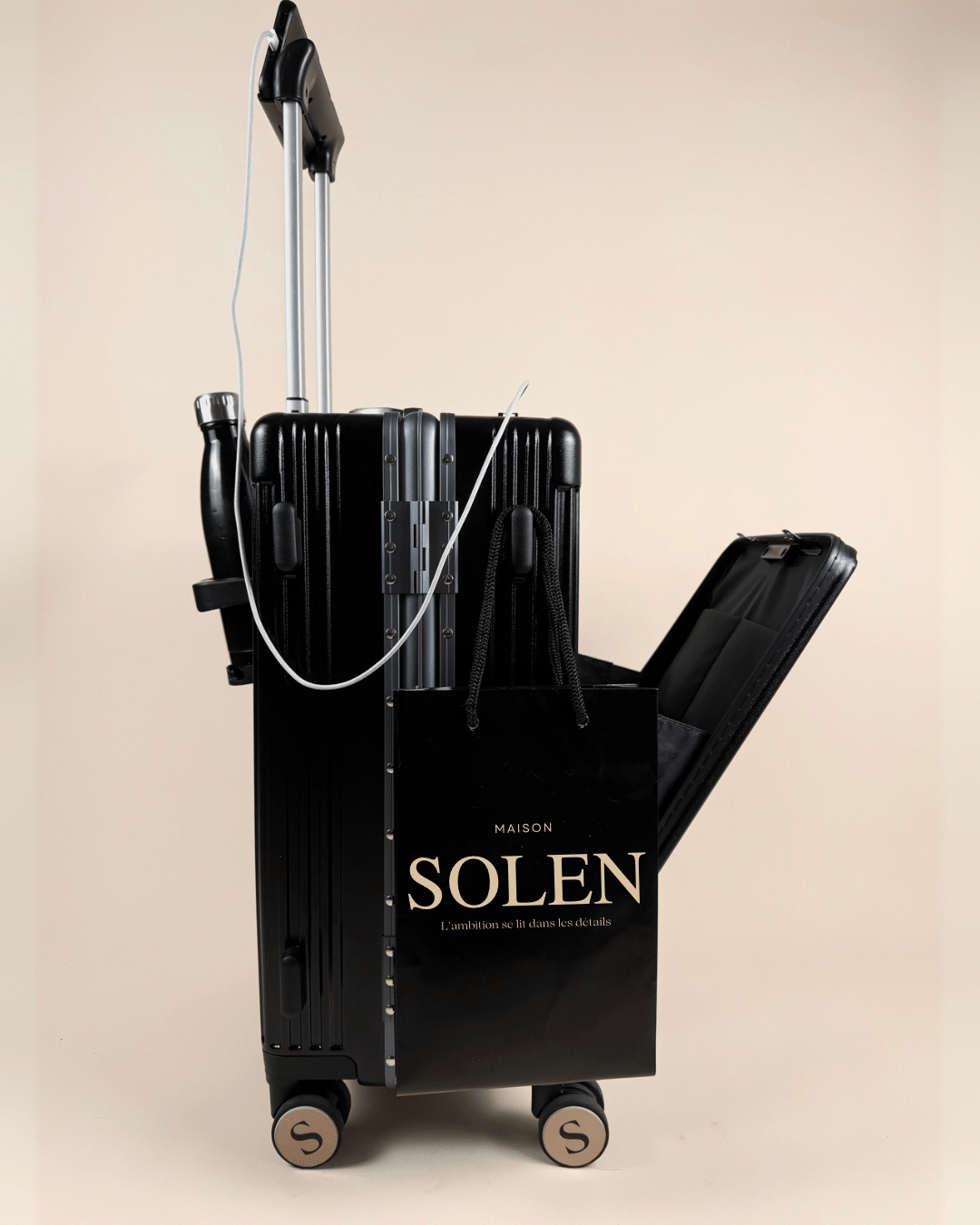 Valise premium aluminium noire Maison Solen avec port USB intégré et sac cadeau luxe, trappe frontale ouverte.